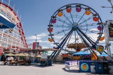 Kaliforniya 'daki Santa Cruz sahilinde güneşli bir öğleden sonra soldaki dev ayı, gülen gondollu bir dönme dolap, şemsiyeler ve yiyecek standları gösteriyor..