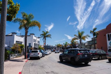 Şehir merkezindeki Capitola, California 'nın gün ortası manzarası, palmiye kuyruklu dükkanlar ve kafeler, kaldırımlardaki arabalar, yerliler ve ziyaretçiler Capitola Beach' e doğru temiz kaldırımlar boyunca ilerliyorlar..