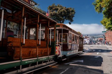 Klasik bir teleferik Fisherman 's Wharf, San Francisco' da bir köşede bekliyor. İzler körfeze doğru eğriliyor. Tuğla binalar, rıhtımlar, sis ve gün ortası ışığı..