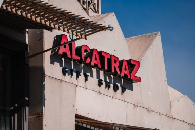 San Francisco, Alcatraz Adası 'ndaki endüstriyel cephede kalın kırmızı ALCATRAZ neonuna açık gün ışığında açısal beton, metal aksesuarlar ve keskin gölgelerle yaklaşın..