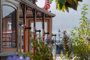 San Francisco teleferiği Balıkçı İskelesi ya da Embarcadero yakınlarında, bayrak, ahşap paneller, demir saplar ve yumuşak gün ışığında çiçekler ve sığ alan derinliğinde durur..