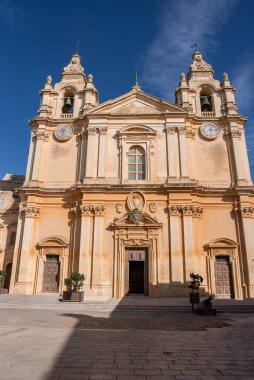 Mdina, Malta 'daki St. Pauls Katedrali' nin ön manzarası, sıcak kireçtaşından yapılmış ikiz saat ve çan kuleleri, şeffaf ışık pilasterler ve kornişler üzerine keskin gölgeler bırakıyor..