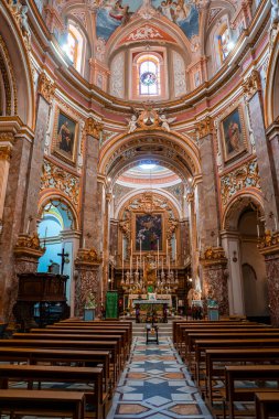 Mdina, Malta 'daki merkez koridor manzarası altın sunak, pembe mermer sütunlar, fresk kubbe, papaz odası pencereleri ve gündüz boş sıraları gösteriyor..