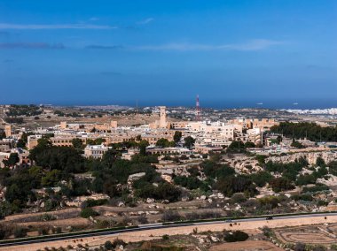 Gündüz vakti yükselen Mdina, Maltas eski başkenti, kaleler, katedral kubbesi ve çan kuleleri, dağ sırtı düzeni, teraslı alanlar ve uzak Akdeniz.