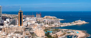 Sliema ve St. Julians, Malta 'nın öğlen hava görüntülerinde Pordomates İş Kulesi, tatil merkezleri, marinalar, kumlu koylar, kayalık plajlar ve turkuaz otel havuzları görülüyor..