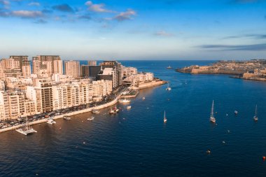 Altın saatinde Valletta, Malta ve Sliema 'nın havadan görünüşü, yelkenliler, yatlar, eğimli gezinti güverteleri, kireçtaşı kaleleri, dalgakıranlar ve sakin mavi sularla..