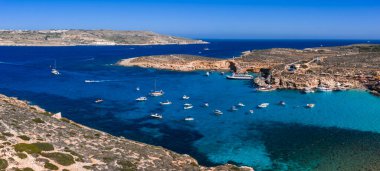 Hava görüntüsü Malta 'nın Comino Adası' ndaki Mavi Göl 'ü gösteriyor. Gemiler demirlemiş, kireçtaşı kıyıları, kobalt suları, Gozo ve Malta' nın ötesinde..