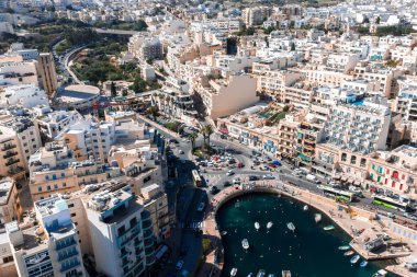 Sliema 'nın yüksek açılı hava manzarası, kireçtaşı binaları, teraslı çatıları, demirli tekneleri, eğimli gezinti güverteleri, kafeleri ve öğle vakti kalabalık bir kavşağı olan Malta limanı..