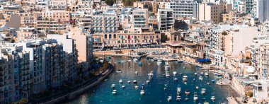 Sliema, Malta 'nın havadan görünüşü, yükselen kireçtaşı ve modern apartmanlarla korunaklı tekne ve yatlar, parlak öğlen ışığı, berrak turkuaz su ve gezinti güvertesi..