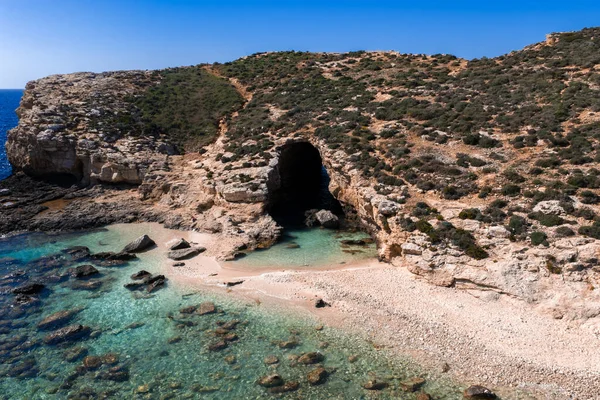 Hava görüntüsü Comino, Malta Mavi Göl Koyu 'nda deniz mağarası, kireçtaşı uçurumlar, beyaz çakıl taşı plajı ve parlak öğle güneşinde turkuaz su, yüksek kontrastlı