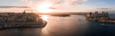 Günbatımında Valletta, Malta 'da kireçtaşı duvarlar, Basilica kubbesi, St. Pauls kulesi ve Fort Manoel' in havadan görünüşü kesilen tekneler Sliema ve St. Julians 'a doğru uyanır..
