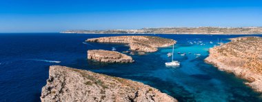Hava görüntüsü, Comino, Malta 'daki Mavi Göl' ü gösteriyor. Turkuaz körfez, kireçtaşı uçurumlar, demirli yelkenliler ve parlak öğle güneşi altında Gozo ve Malta 'dan uzakta..