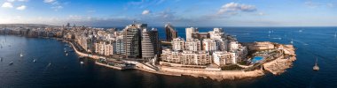 Valletta, Malta 'nın havadan görünüşü, yelkenli tekneli iki liman, modern kuleler, kireçtaşı terasları, deniz suyu havuzu ve altın saat tahkimatları arasındaki kayalık yarımada.