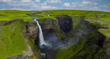 Hava görüntüsü Haifoss 'un İzlanda' da dik bir kanyona düştüğünü gösteriyor. Yumuşak gün ışığı bazalt kayalıkları, üsten sis yükseliyor ve vadiden bir nehir geçiyor..