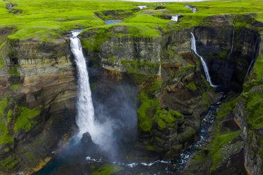 Hava görüntüsü, İzlanda Highlands 'taki Fossa nehrinin yakınındaki Haifoss ve Granni şelalelerini gösteriyor. Gün ışığında kanyondan çıkan bir nehir gibi sisli bazalt geçidine ikiz damlalar düşer..