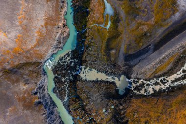 Örülmüş buzul nehirleri, İzlanda 'daki karanlık lav tarlalarından ve yosunlu tundralardan geçer. Landmannalaugar yakınlarında, yumuşak gün ışığında yüksek irtifadan çekilir..