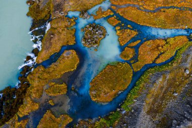 Hava görüntüsü, Landmannalaugar ya da Sigoldugljugfur yakınlarındaki İzlanda dağlık arazilerinde, deniz yosunu ve yosun yeşil tundrası üzerinde örülmüş buzul akıntıları gösteriyor..