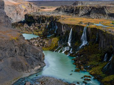 Hava görüntüsü İzlanda Highlands 'taki Sigoldugljufur Kanyonu' nu gösteriyor. Yumuşak gün ışığı altında birçok ince şelalesi ve mineral mavisi buzul nehri olan bir bazalt vadi..