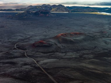 Havadan bakıldığında İzlanda, Landmannalaugar yakınlarındaki bir volkanik ovada kül külü olduğu görülüyor. Rhyolite dağlarına ve şafak vakti buzul göllerine doğru çakıllı bir yol esiyor..