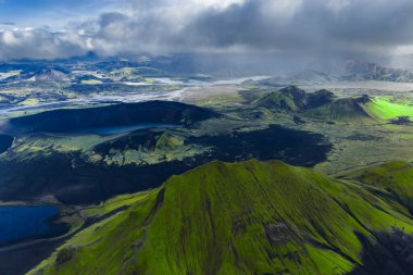 Fjallabak Doğa Rezervi, İzlanda 'daki Landmannalaugar' ın havadan görünüşü yosunlu ryolit dağları, karanlık lav alanları, göller ve tepeler boyunca ışık demetleri..