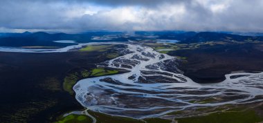 İzlanda 'da, Landmannalaugar ve Tungnaa veya Skafta sistemleri yakınlarındaki karanlık volkanik ovalarda, yosun ve uzak dağlarla örülmüş erimiş su kanallarının hava görüntüsü..