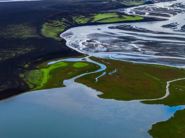Hava yılanı nehirleri İzlanda 'nın dağlık arazilerindeki siyah kumlar ve yosunlardan geçerek yumuşak ve dağınık bir ışık altında mavi bir lagüne akar..