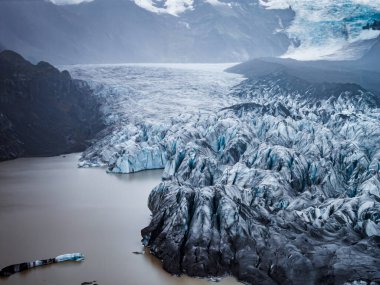 Buzul dili ve İzlanda 'daki Vatnajokull Ulusal Parkı' ndaki sütlü göl manzarası. Mavi yarıklar, küçük buzdağları, sis ve bulutlu ışık soğuk bir hava yaratır..