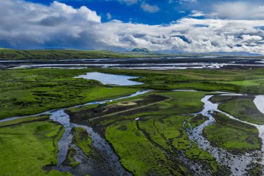 Landmannalaugar yakınlarındaki bir İzlanda nehir deltası, örülmüş kanallar ve göller, volkanik tepeler ve uzak karlı tepeler, zümrüt yosunları ve siyah kumlar..
