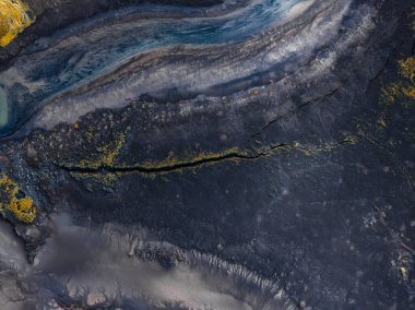 Landmannalaugar yakınlarındaki İzlanda volkanik dağlarının yukarıdan görünüşü, uzun bir çatlak, kül grisi ve kömür kayası, sarı yeşil yosun ve yumuşak bulutlu ışık