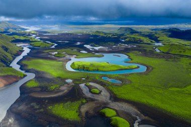 Landmannalaugar veya Sigoldugljufur 'daki İzlanda dağlarının hava manzarası, zümrüt yosunları, buzullu nehirler, turkuaz göller ve gündüz siyah lav tarlaları..