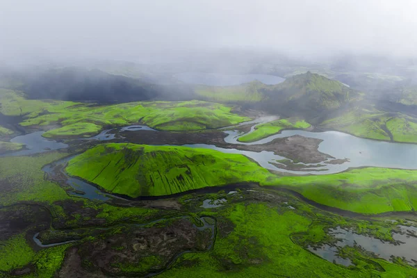 Landmannalaugar yakınlarındaki İzlanda Highlands 'ta yosun yeşili tepeler, örülmüş nehirler, lav tarlaları ve ryolite sırtları alçak bulutlar ve yayılmış gün ışığı..