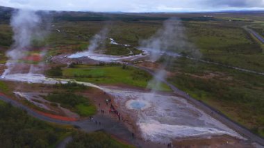 Hava genişliği, İzlanda 'daki buharlı Haukadalur Geysir bölgesini, mavi havuzları, beyaz terasları, kırmızı toprağı, yeşil ovayı, tahta kaldırımları, yolları ve tundraları gösteriyor..