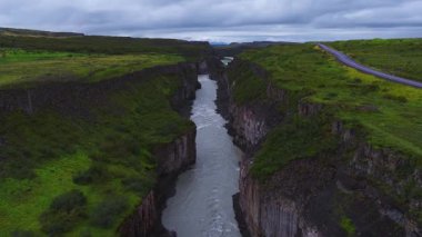 Havadan bakıldığında, Haifoss yakınlarındaki İzlanda 'da bazalt kanyonu kesen bir buzul nehri görülüyor. Çevresinde asfalt yol, hızlı su, akıntılar ve bulutlu ışık altındaki havuzlar var..