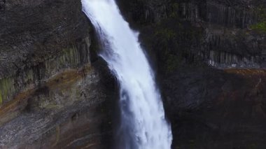 Havadan yakından bakıldığında Thjorsardalur, İzlanda 'da Haifoss şelalesi görünüyor. Beyaz su bazalt sütunlarını kesiyor, koyu kayalarda yosun, yukarıda örülmüş nehir, yaz ortasında çekiliyor..