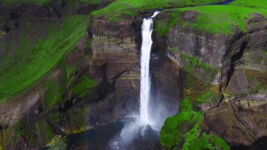 Hava aracı görüntüsü Thjorsardalur, İzlanda 'da Haifoss ve Granni' yi gösteriyor. Su kayalık bir kanyona dalıyor. Sprey gökkuşağı, bazalt sütunlar ve katmanlar görünür hale geliyor..