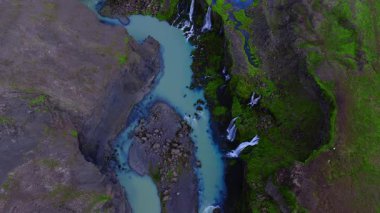 İzlanda 'daki hava manzarası Sigoldugljufur kanyonu, sütlü turkuaz nehir, yosun kaplı şelaleler, örgülü kanallar, çakıl adası ve yumuşak gün ışığı hareketini gösteriyor..