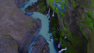 Yukarıdan bakıldığında Sigoldugljufur, İzlanda 'da akuamarin ile beslenmiş bir nehir bazalt oyması görülüyor. Gün ışığında yosunlu adalarda kademelerde ve örgülerde çağlayan sular..