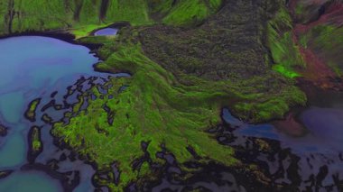 Yazın yapılan İHA çekimlerinde siyah lav, turkuaz krater gölleri, ryolit yamaçları ve İzlanda dağlık kesimlerinde yavaş süpürme tavasıyla örülmüş kanallar zümrüt yosunları görülüyor..