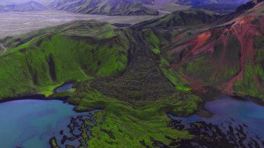 Landmannalaugar, İzlanda 'daki hava manzarasına göre lav akıntıları turkuaz gölleri, örülmüş düz siyah kum marjları ve açık yaz ışığında kırmızı ryolit yamaçları ile buluşuyor.
