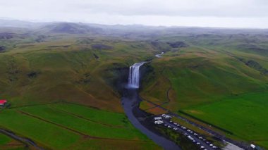 Skogafoss şelalesi İzlanda 'daki yeşil uçurumlardan akıyor. İzlanda 'nın en popüler şelalelerinden biri olan Skogafoss şelalesinin 4k hava ağır çekim görüntüsü..