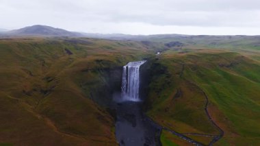 Skogafoss şelalesi İzlanda 'daki yeşil uçurumlardan akıyor. İzlanda 'nın en popüler şelalelerinden biri olan Skogafoss şelalesinin 4k hava ağır çekim görüntüsü..