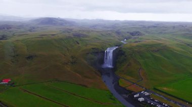 Skogafoss şelalesi İzlanda 'daki yeşil uçurumlardan akıyor. İzlanda 'nın en popüler şelalelerinden biri olan Skogafoss şelalesinin 4k hava ağır çekim görüntüsü..