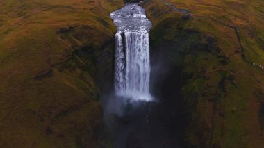 Skogafoss şelalesi İzlanda 'daki yeşil uçurumlardan akıyor. İzlanda 'nın en popüler şelalelerinden biri olan Skogafoss şelalesinin 4k hava ağır çekim görüntüsü..