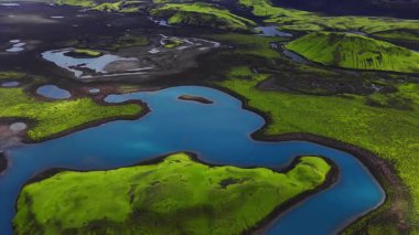 İzlanda volkanik dağları üzerindeki hava taraması turkuaz göller, dolambaçlı nehirler, yosunlu kraterler, tuff tepeleri ve yaz aylarında yumuşak ufuk sisli siyah lav tarlaları gösteriyor..