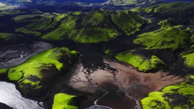 Drone, Landmannalaugar, İzlanda 'daki konik kraterler, siyah kül ovaları, yeşil yosunlar, örülmüş nehirler ve bakır tortu vantilatörleri üzerinde hareket eder.