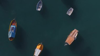 Marsaxlokk limanındaki Malta Luzzus ve botlarının havadan aşağı görüntüsü, Malta. Tekneler şamandıra ve çizgiler, yumuşak alçak açı ışığı, uzun gölgeler etrafında dönüp durur..