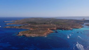Comino 'nun, Blue Lagoon' un ve Malta 'daki St. Marys Kulesi' nin havadan görüntüsü. Tekneler, turkuaz suda, parlak öğlen ışığı altında canlı mavilerle uyanır..