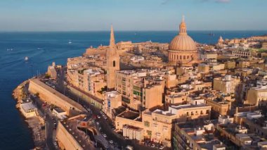 Valletta, Malta 'nın alacakaranlıktaki hava manzarasında bazilika kubbesi, profesyonel katedral kulesi, kaleli duvarlar, deniz duvarları, botlar, dar sokaklar, balkonlar, teraslar ve kıyı yolları görülüyor..