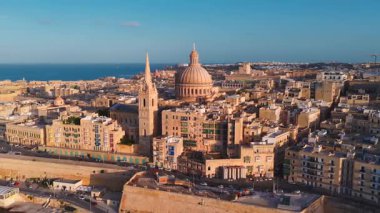 Valletta üzerindeki hava günbatımında, Malta dar sokakların üzerinde Carmelite Kilisesi kubbesi ve St Pauls Pro Katedrali ile kale duvarları, rıhtım yolları ve botlar görülüyor..