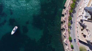 Sliema, Malta 'nın havadan aşağı manzarası, gezinti güvertesi, deniz duvarı, kıyı yolu, aydınlık binalar ve parlak gün ışığı ve renkte sürüklenen beyaz bir yat.